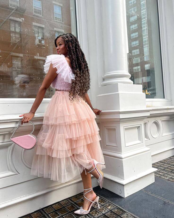 Foto de mujer usando un vestido naranja claro y blusa lila con bolso pequeño rosa